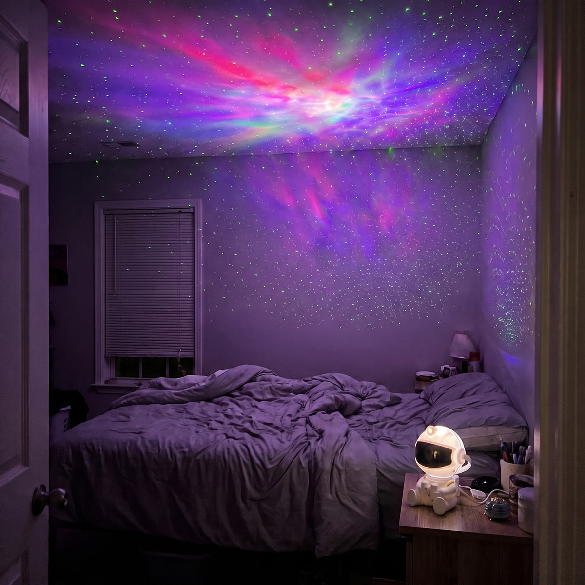 Bedroom at night seen from the doorway, the small astronaut projector on the nightstand lighting the whole ceiling