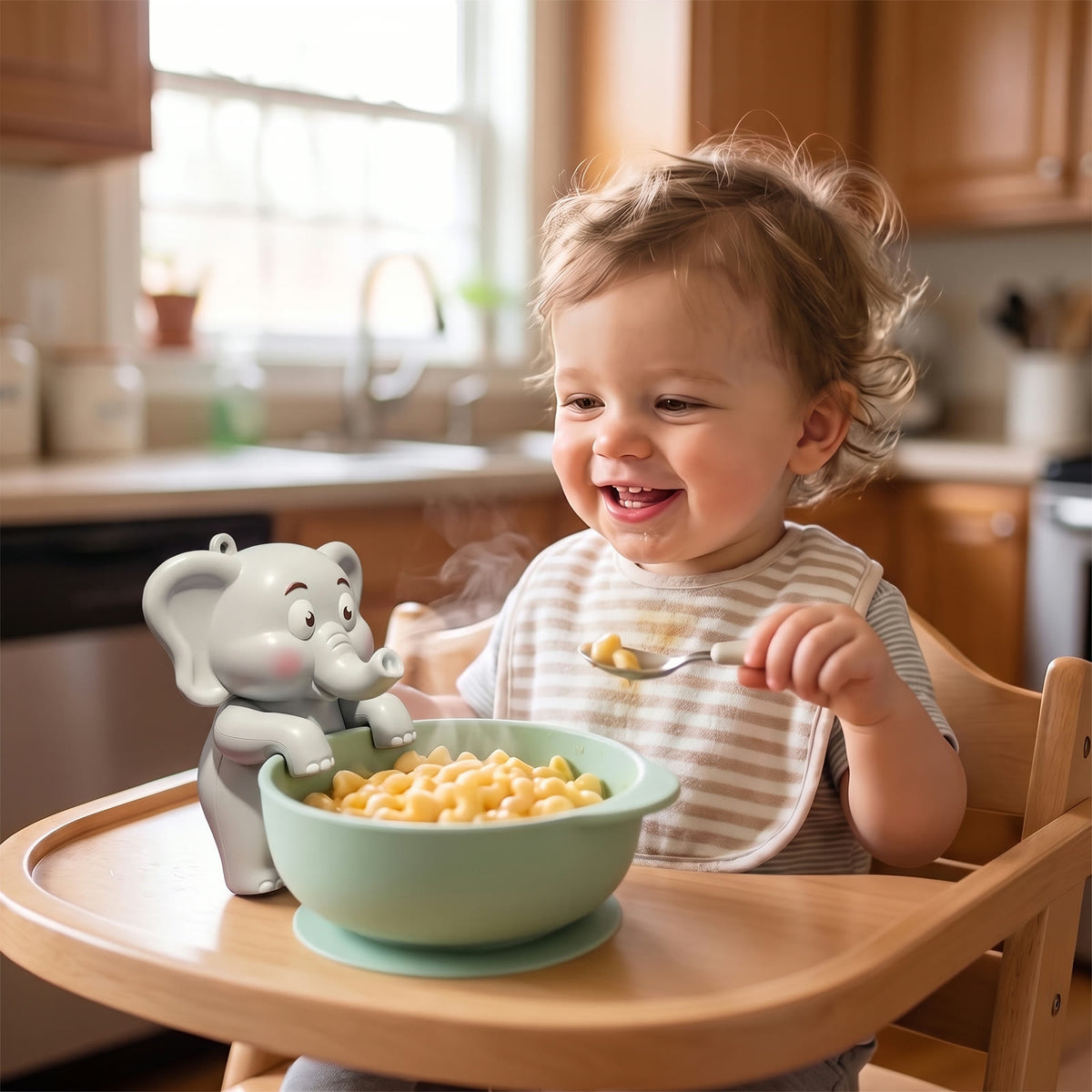 Toddler in a high chair smiling at the Cool Bite Buddy elephant fan cooling a bowl of mac and cheese