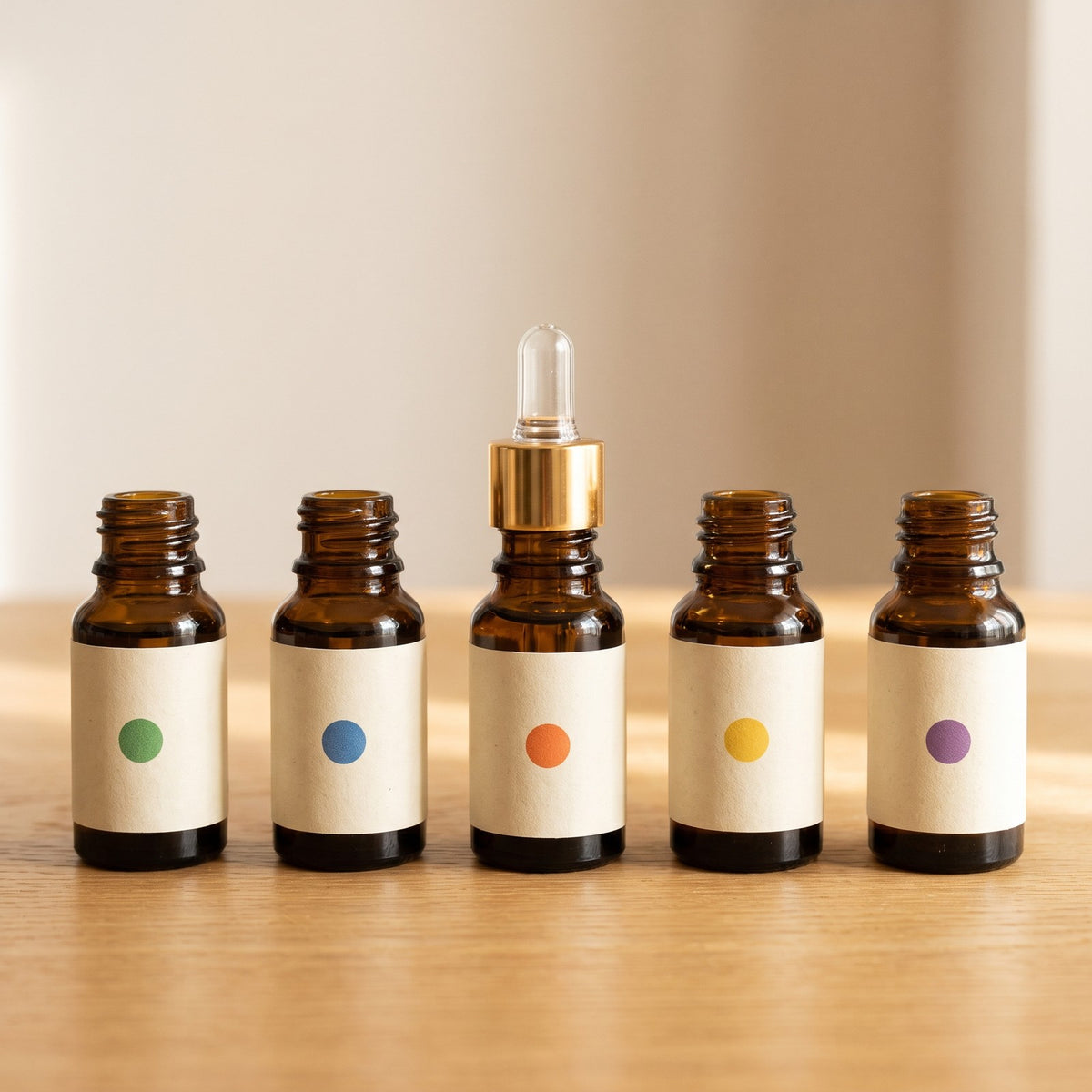 A row of 5 ml amber essential oil bottles with their scent labels and a glass dropper