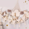 Beige Macrame Stuffed Animal Hammock hung across a corner, filled with teddy bears and dolls