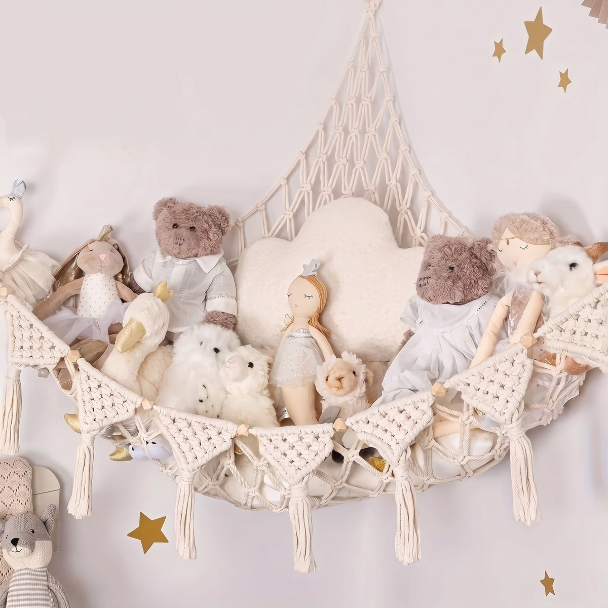 Beige Macrame Stuffed Animal Hammock hung across a corner, filled with teddy bears and dolls