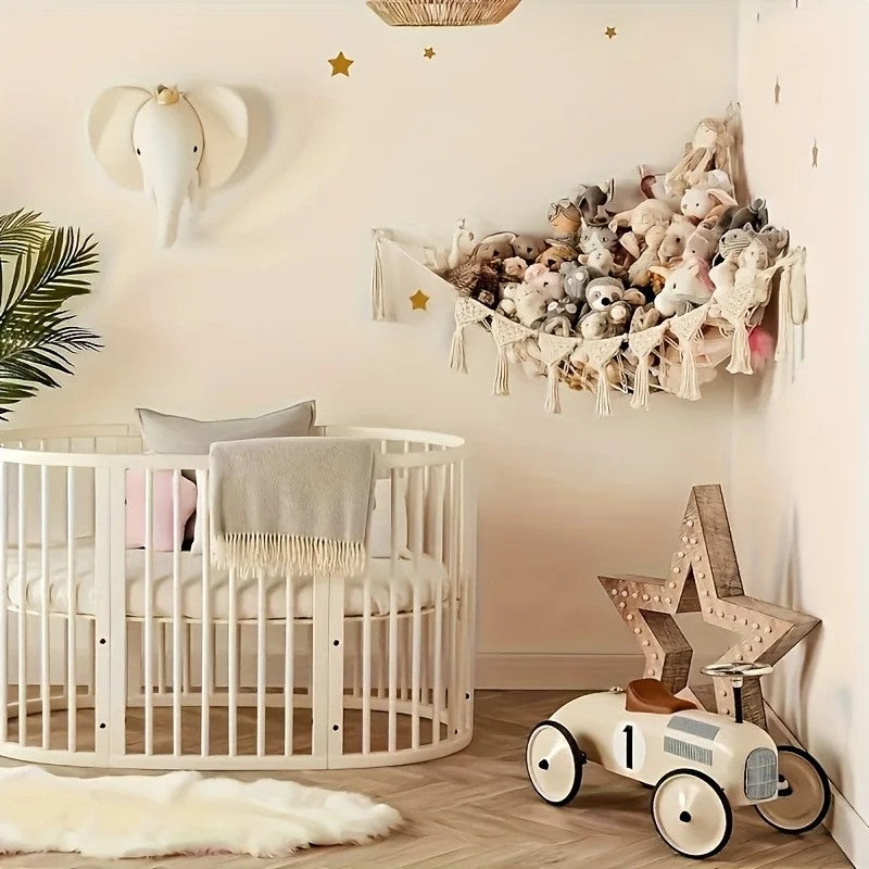 Beige toy hammock full of stuffed animals in the corner of a nursery, up off the floor