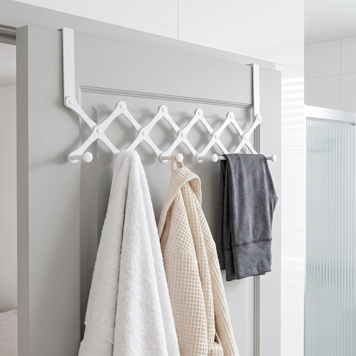 Rewear Rack in white on a bathroom door holding a towel, a robe and leggings