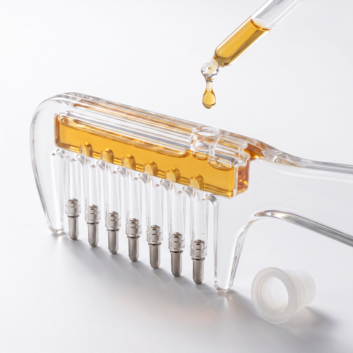 Serum dropping from a dropper into the Scalp Serum Applicator Comb reservoir