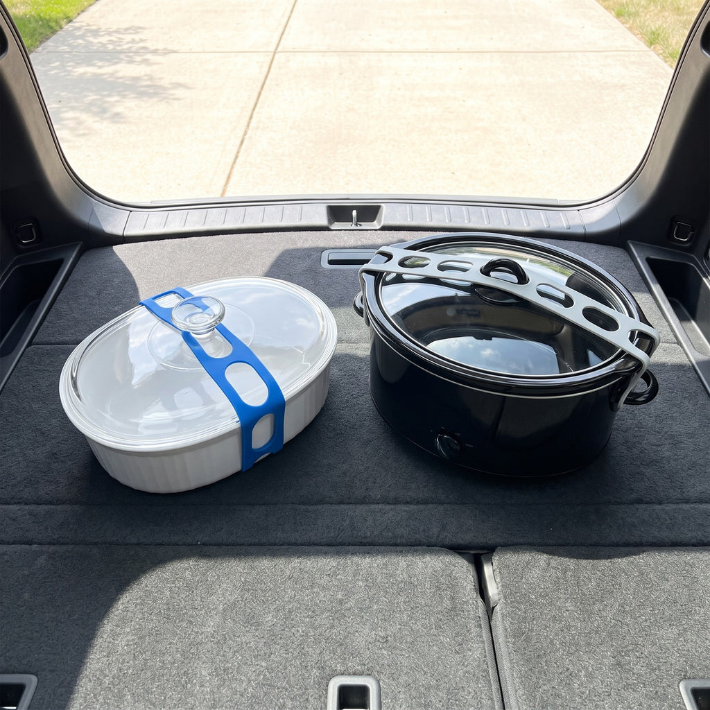 Casserole dish and slow cooker in a car trunk, each lid held down by a lid strap