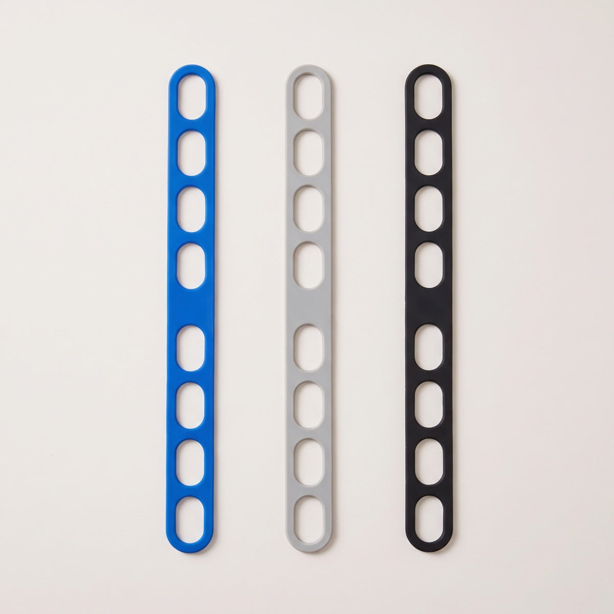 The lid strap in its three colors side by side: blue, grey and black
